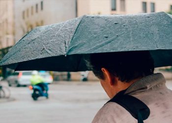 Una persona transita por la calle bajo un paraguas