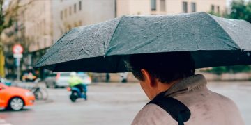Una persona transita por la calle bajo un paraguas