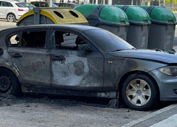 Coche calzinado junto a unos contenedores a los que se les prendió fuego